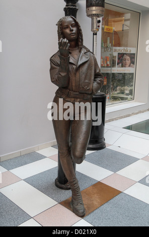 Eine Frau lehnte sich gegen einen Laternenpfahl, einer der mehrere Bronze-Skulpturen rund um die Altstadt, Bratislava, Slowakei. Stockfoto