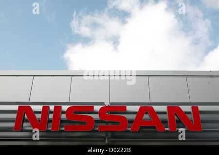 Nissan Auto Firmenlogo bei einem Autohändler mit blauem Himmel dahinter. Stockfoto