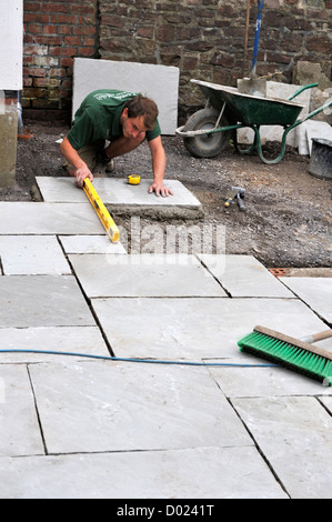 Unter Verwendung eines Niveaus während der Installation von Naturstein Pflastersteine Stockfoto