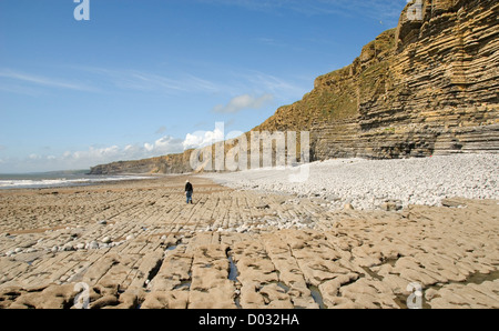 Frau zu Fuß entlang der Küste in der Nähe von steilen Klippen, in der Nähe von Nash Point, Glamorgan Heritage Coast, Wales, UK Stockfoto