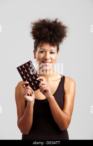 Schöne afrikanische Frau hält eine riesige dunkle Schokolade Stockfoto