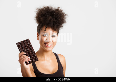 Schöne afrikanische Frau hält eine riesige dunkle Schokolade Stockfoto