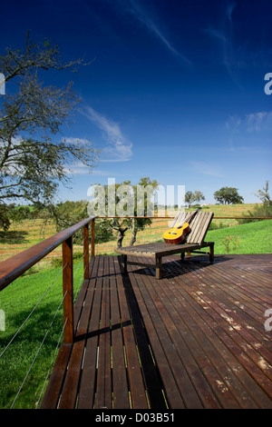 Holz-Ferienhaus mit einem schönen Balkon und einem Longchair mit einer Gitarre an der Spitze Stockfoto