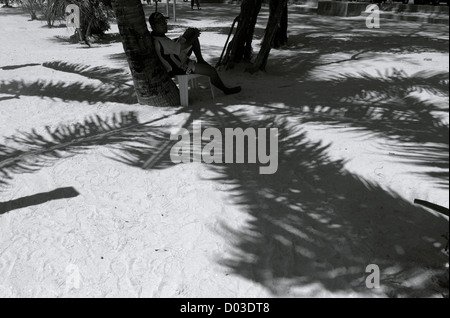 Strand-Verkäufer sitzt unter Schatten der Palme, Thailand Stockfoto