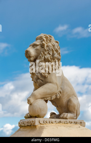 Statue eines Löwen mit Ball vor blauem Himmel Stockfoto