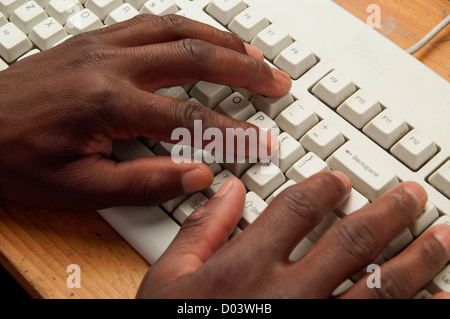 Afrikanischer Mann Hände auf grauen Computertastatur tippen Stockfoto