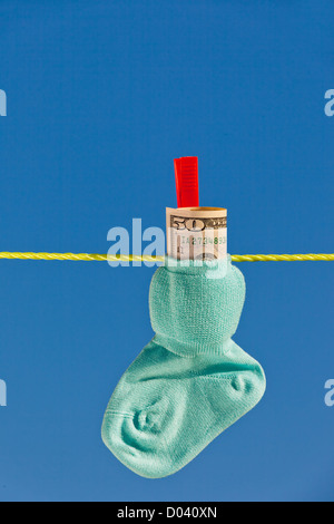 Baby Socken auf der Wäscheleine mit Dollarnoten. Blauer Himmel. Stockfoto