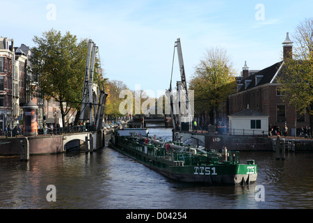 Ein Lastkahn durchläuft eine geöffnete Brücke im Zentrum von Amsterdam. Stockfoto