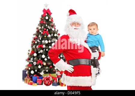 Santa Claus und kleines Kind posiert vor einem geschmückten Tannenbaum isoliert auf weißem Hintergrund Stockfoto