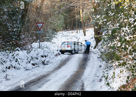 Auto nicht in der Lage auf einen Hügel auf einer vereisten Schnee hinab abgedeckt Feldweg, Surrey, England. Stockfoto