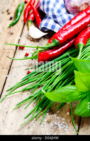 Knoblauch, Basilikum, Schnittlauch und Chilischoten auf einer hölzernen Tischplatte Stockfoto