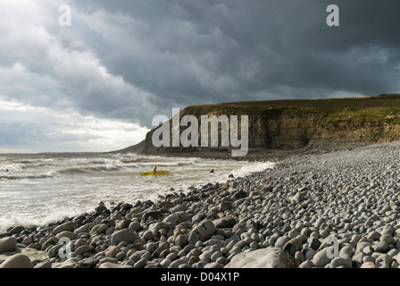 Surfer, steinigen Strand und dramatischen Jurassic Klippen unter Gewitterhimmel in Southerndown in Süd-Wales. Stockfoto