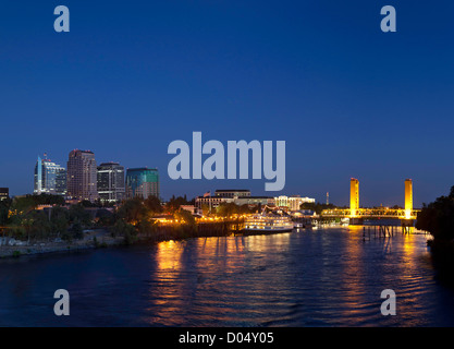 Blick auf die Skyline der Stadt Sacramento in der Abenddämmerung, einschließlich Stadtzentrum gelegene Gebäude, das Delta King River Boot und die Tower Bridge. Stockfoto