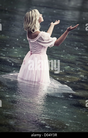 eine Frau im Wasser stehn und genießen den Regen Stockfoto