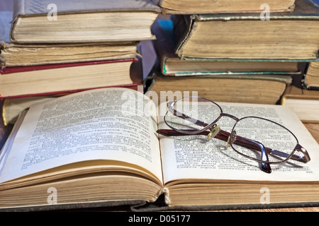 Stapel alter Bücher mit Brille auf Holztisch Stockfoto