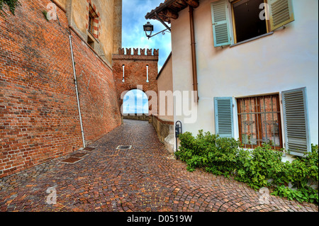 Schmalen gepflasterten Straße zwischen Haus und Ziegel Wand der mittelalterlichen Burg in Barolo, Italien. Stockfoto