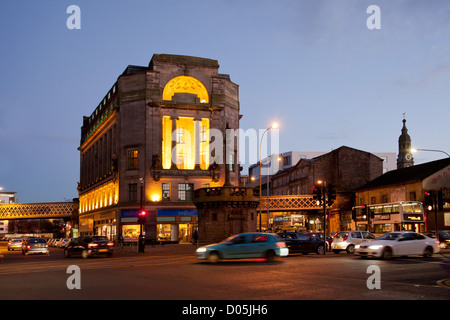 Verkehr in Glasgow Cross bei Sonnenuntergang, mit dem Mercat Gebäude (1922) und der mercat Cross (1929-30). Schottland, Großbritannien. Stockfoto