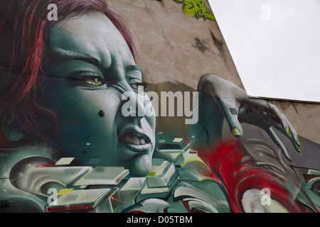 Graffiti von höhnischen das Gesicht einer Frau mit greifen Hand, grüne Augen und grün lackierten Fingernägel über einem Autohändler in Bristol Stockfoto