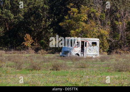 Eine vernachlässigte alte Milchwagen sitzt auf einer Weide gegen eine Reihe von Bäumen in einen Acker. Stockfoto