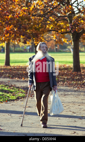 Porträt eines älteren Mannes mit langem, weißem Bart, der mit einem Gehstock spazieren geht, Regent's Park, London, England, Großbritannien. Stockfoto