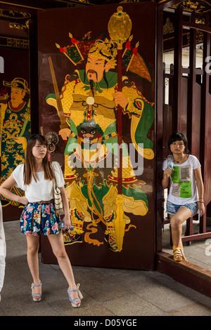 Eine junge, modische Frau steht an der Pforte des Chenghuang Miao oder City God Temple in Yu Yuan Gardens Basar Shanghai, China Stockfoto