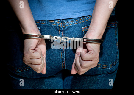 Eine Frau wird verhaftet und in Handschellen vor dem Transport ins Gefängnis gelegt. Stockfoto