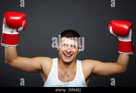 Porträt von glücklich junger Mann im roten Boxhandschuhe Blick in die Kamera Stockfoto