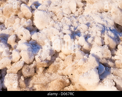 Einstellung Sonne Gießen orangefarbenes Licht auf Frost bedeckt Klumpen von Eis und Schnee Stockfoto