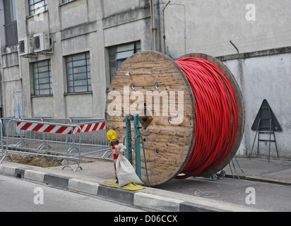 Ausgrabungen auf einer Baustelle während der Installation von elektrischen Hochspannungskabel und großen hölzernen Spule Stockfoto