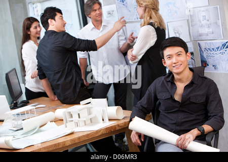 Architekt Holding Blaupause mit seinem Team im Hintergrund Stockfoto