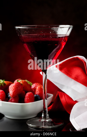 Foto von Kelch mit Cocktail mit Beeren auf rot beleuchteten backgroud Stockfoto