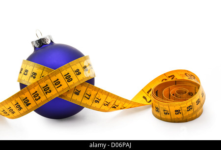 Maßband um eine Christbaumkugel Konzept symbolisiert Weihnachten Gewicht gewinnen durch den Verzehr von zu viel Essen. Stockfoto