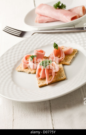 Foto von Cracker Vorspeise mit Schinken und Petersilie auf weißer Holztisch Stockfoto