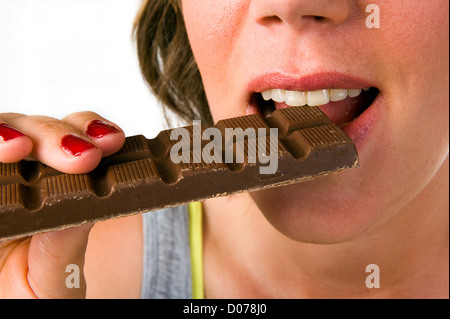 Eine junge Frau, die ein Stück Schokolade essen Stockfoto