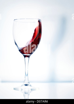 Rotwein in ein Glas künstlerische dynamisches Foto auf hellen Hintergrund isoliert Stockfoto