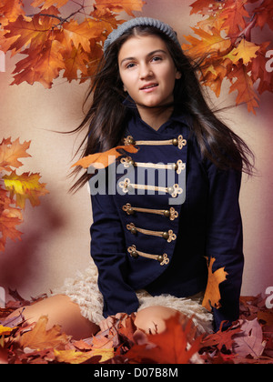 Teenager-Mädchen sitzen auf gefallenen Herbst Blätter künstlerische Herbst Mode Porträt Stockfoto