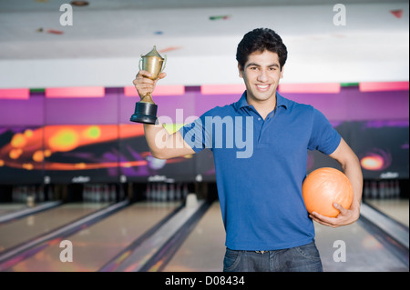 Junger Mann hält eine Bowling-Kugel in einer Bowlingbahn Stockfoto