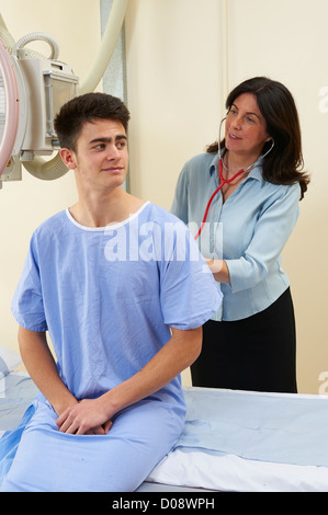 Arzt mit Stethoskop, um ein Teenager zu untersuchen, die auf eine X-Ray Tisch in einer Röntgen-Abteilung Stockfoto