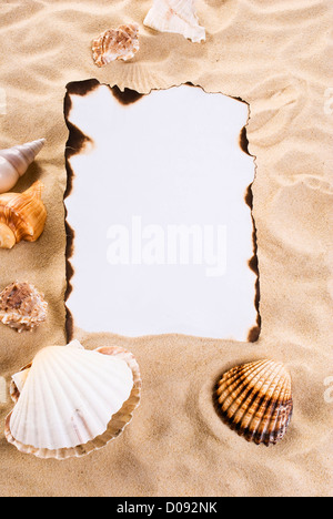 Verbranntes Papier auf dem Sand mit Muscheln Stockfoto