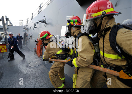 Matrosen üben Brandbekämpfung Techniken während einer Schadensbegrenzung Drill an Bord der geführte Flugkörper-Zerstörer USS Jason Dunham (DD Stockfoto