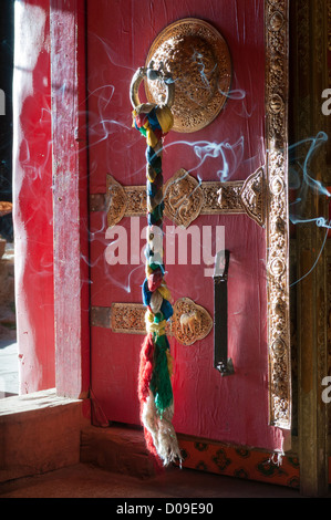 Weihrauch weht hinter verzierten Tür, der Eingang zum Tempel, Reting Kloster, Tibet, China bewacht Stockfoto
