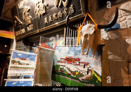 Yak-Schädel mit Hörnern hängen mit Gobelin PortalEin Palast im Souvenir-Shop in der Nähe von Barkhor Square, Lhasa, Tibet Stockfoto