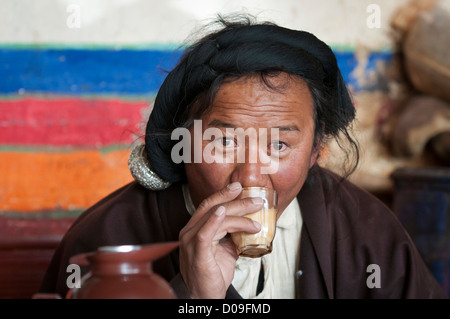 Mit Silber sein Haar geflochten nippt tibetische Hirten Yak Buttertee im Straßencafé, Namtso, Tibet, China Stockfoto