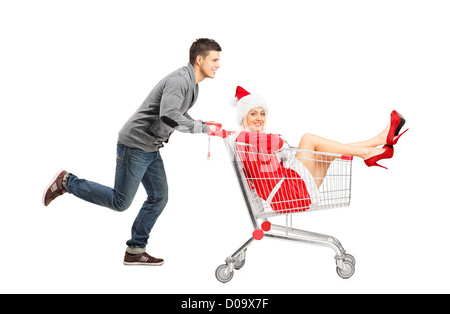 Ein Kerl schob eine Frau trägt Weihnachtskostüm in einem Einkaufswagen isoliert auf weißem Hintergrund Stockfoto