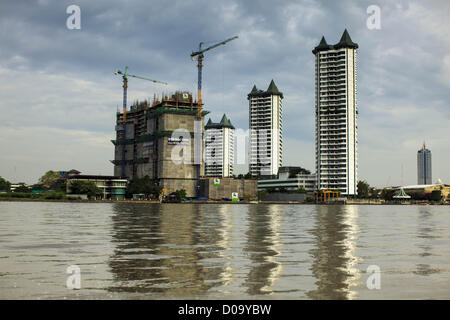 17. November 2012 - Bangkok, Thailand - neue Wohnungsbau auf der westlichen Seite des Chao Phraya Flusses in Thonburi Abschnitt von Bangkok.  Bangkok war früher bekannt als das "Venedig des Ostens '' aufgrund der Anzahl der Wasserstraßen, die Kreuz und quer die Stadt gekreuzt. Nun die meisten der Wasserstraßen ausgefüllt aber Boote und Schiffe nach wie vor eine wichtige Rolle im täglichen Leben in Bangkok. Tausende von Menschen pendeln täglich auf dem Chao Phraya Express Boote und Schnellboote, die ply Khlong Saen Saeb oder Boote verwenden, um die Kanäle auf der Thonburi-Seite des Flusses zu erkunden. Boote werden verwendet, um co zu schleppen Stockfoto