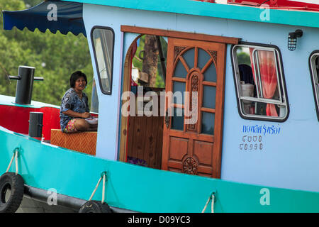 17. November 2012 - Bangkok, Thailand - eine Frau auf einem Schlepper auf dem Chao Phraya River in Bangkok. Bangkok war früher bekannt als das "Venedig des Ostens '' aufgrund der Anzahl der Wasserstraßen, die Kreuz und quer die Stadt gekreuzt. Nun die meisten der Wasserstraßen ausgefüllt aber Boote und Schiffe nach wie vor eine wichtige Rolle im täglichen Leben in Bangkok. Tausende von Menschen pendeln täglich auf dem Chao Phraya Express Boote und Schnellboote, die ply Khlong Saen Saeb oder Boote verwenden, um die Kanäle auf der Thonburi-Seite des Flusses zu erkunden. Boote werden verwendet, um die Rohstoffe durch die Stadt Tiefwasser-Häfen für Hol Stockfoto