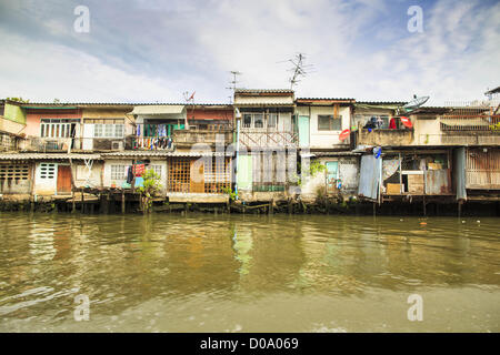 17. November 2012 - Bangkok, Thailand - traditionelle Gehäuse an einem Kanal im Abschnitt "Thonburi" von Bangkok. Bangkok war früher bekannt als das "Venedig des Ostens '' aufgrund der Anzahl der Wasserstraßen, die Kreuz und quer die Stadt gekreuzt. Nun die meisten der Wasserstraßen ausgefüllt aber Boote und Schiffe nach wie vor eine wichtige Rolle im täglichen Leben in Bangkok. Tausende von Menschen pendeln täglich auf dem Chao Phraya Express Boote und Schnellboote, die ply Khlong Saen Saeb oder Boote verwenden, um die Kanäle auf der Thonburi-Seite des Flusses zu erkunden. Boote werden verwendet, um die Rohstoffe durch die Stadt bis tief Wat zu schleppen Stockfoto