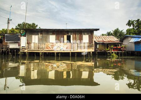 17. November 2012 - Bangkok, Thailand - traditionelle Gehäuse an einem Kanal im Abschnitt "Thonburi" von Bangkok. Bangkok war früher bekannt als das "Venedig des Ostens '' aufgrund der Anzahl der Wasserstraßen, die Kreuz und quer die Stadt gekreuzt. Nun die meisten der Wasserstraßen ausgefüllt aber Boote und Schiffe nach wie vor eine wichtige Rolle im täglichen Leben in Bangkok. Tausende von Menschen pendeln täglich auf dem Chao Phraya Express Boote und Schnellboote, die ply Khlong Saen Saeb oder Boote verwenden, um die Kanäle auf der Thonburi-Seite des Flusses zu erkunden. Boote werden verwendet, um die Rohstoffe durch die Stadt bis tief Wat zu schleppen Stockfoto