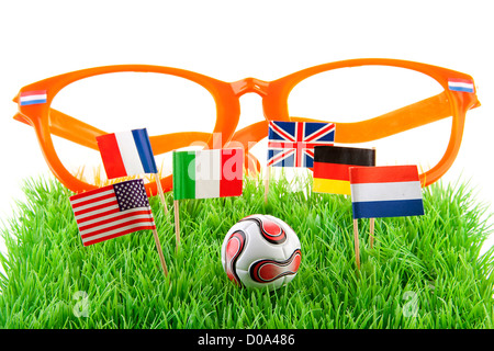 Flags, big orange glasses and ball on soccer field over white background Stockfoto