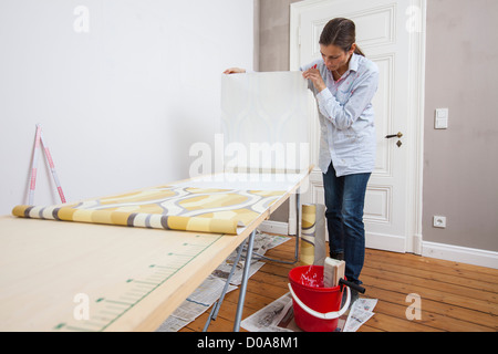 Junge Frau ist ihr Haus renovieren. Tapezieren, neue Tapete. Zum Selbermachen. Stockfoto